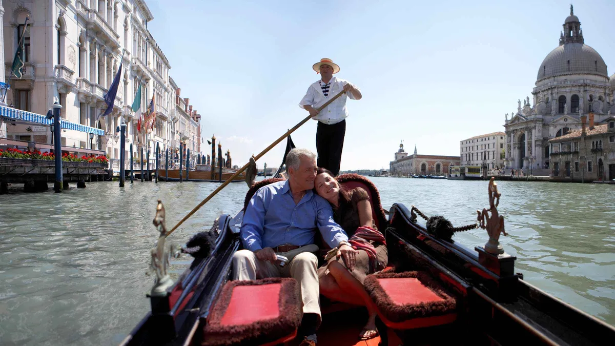 Gondola in an empty back canal lined with weathered brick houses on an off-the-beaten-path gondola ride in Venice, Italy