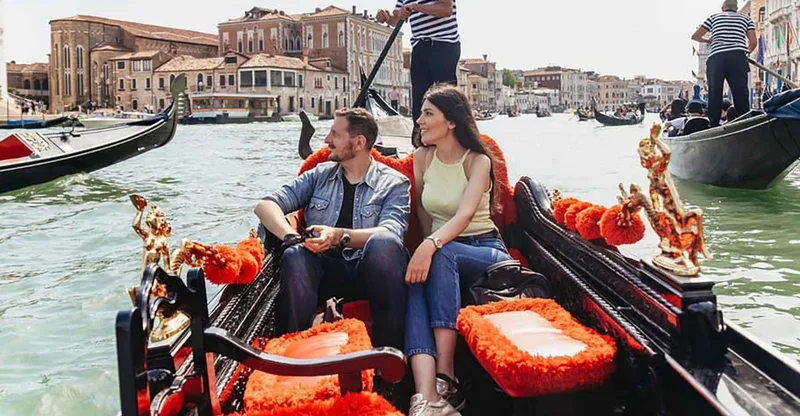 Gondolas passing palazzo facades on the Grand Canal during a gondola ride in Venice, Italy, with a gondolier rowing from the stern