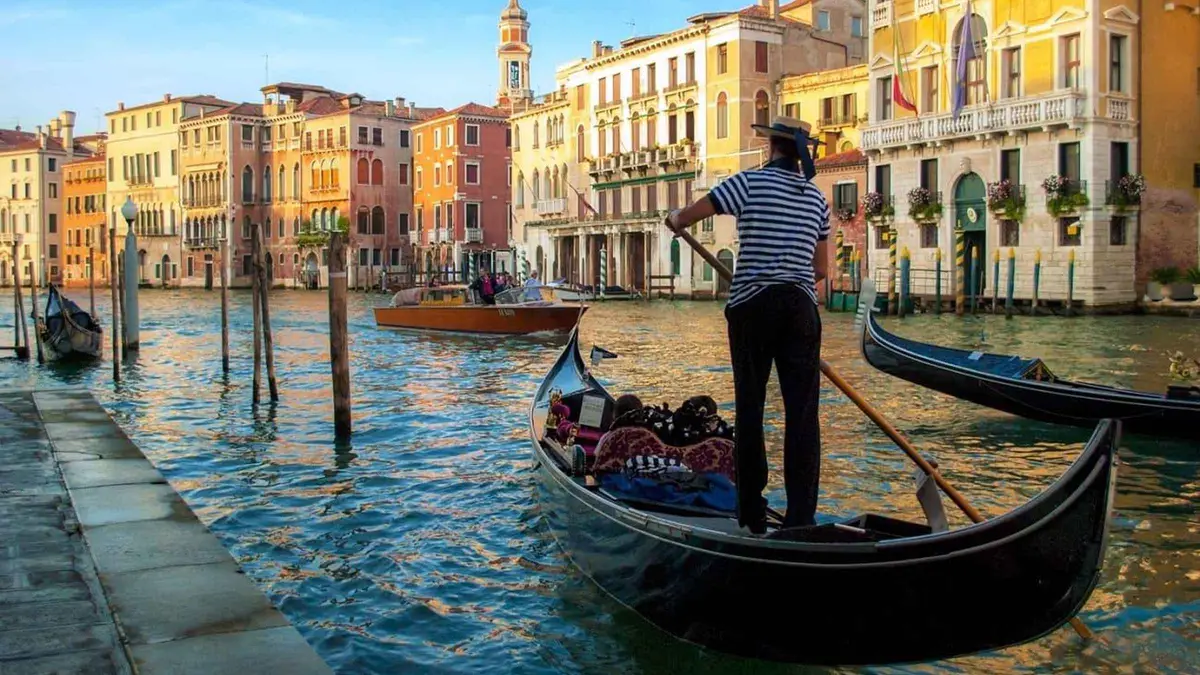 Private gondola with a gondolier in a striped shirt rowing past pastel palazzi on a private gondola ride in Venice, Italy