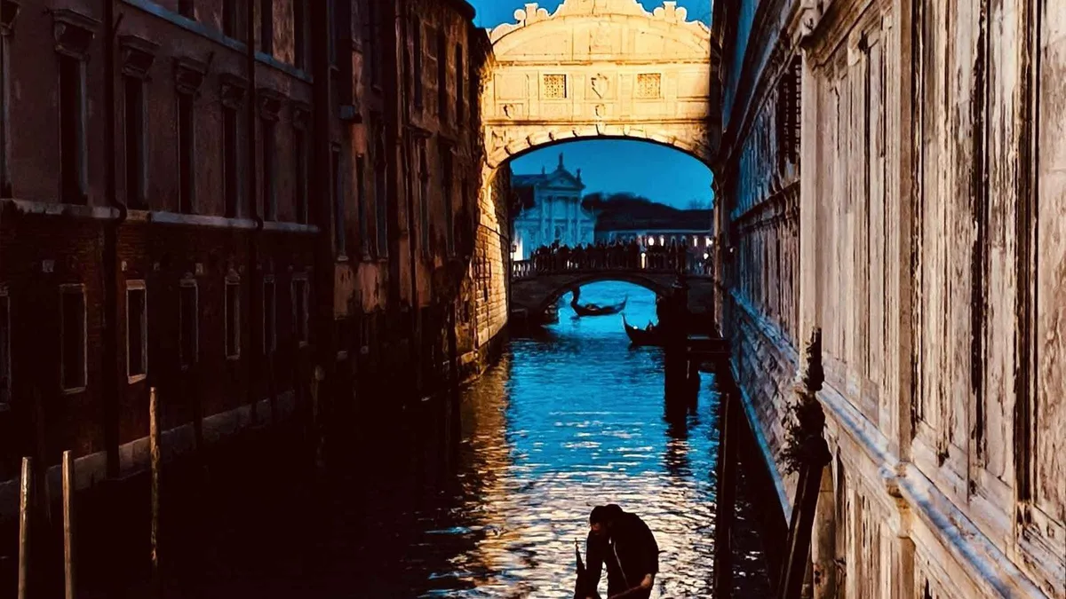 Couple alone in a private gondola passing beneath the Bridge of Sighs at dusk on a romantic gondola ride in Venice, Italy