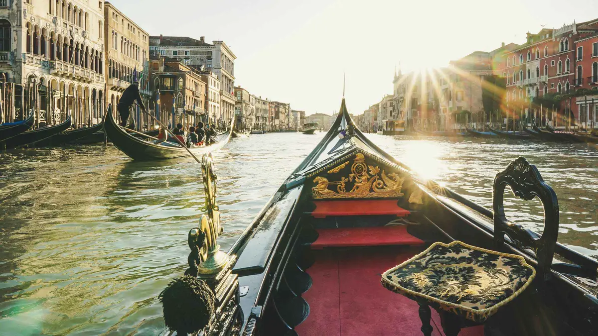Chilled Prosecco bottle and two glasses on the cushioned seat of a private gondola on a Prosecco gondola ride in Venice, Italy
