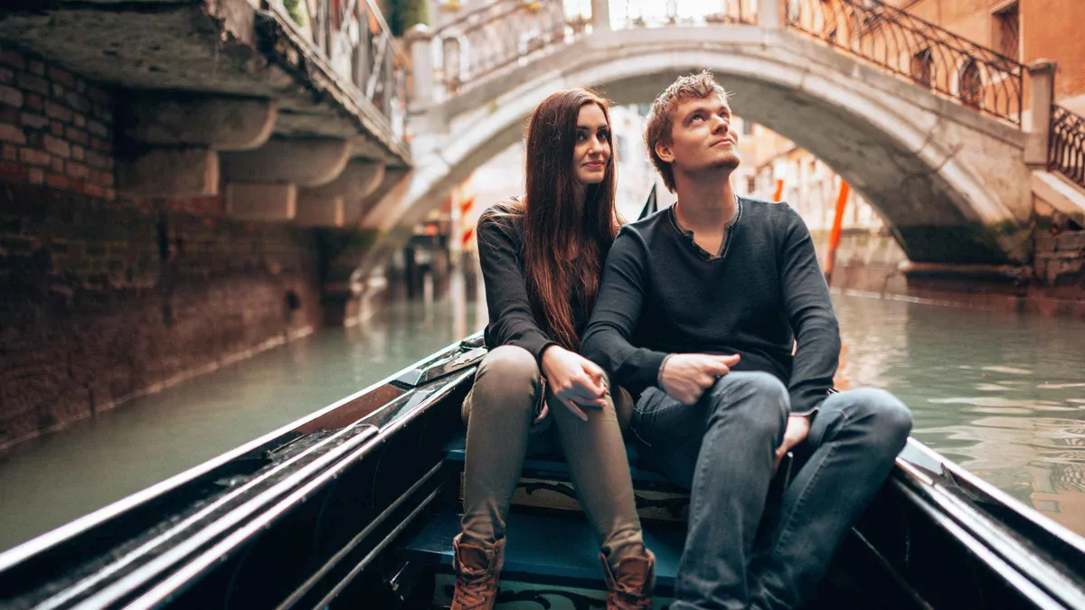 Photographer shooting a couple seated in a private gondola on a canal during a photo-shoot gondola ride in Venice, Italy